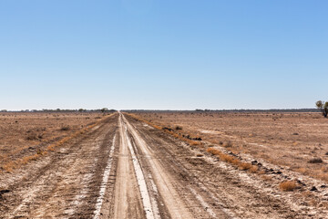 Travelling a remote country dirt road through the unfenced land of a large cattle station in the black soil country of western Queensland, Australia.