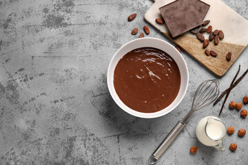 Bowl with delicious hot chocolate, whisk and jar of milk on grunge grey background. Top view