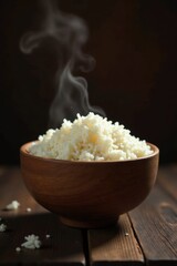 A steaming bowl of freshly cooked rice, presented on a dark wooden surface, evokes warmth and culinary satisfaction.
