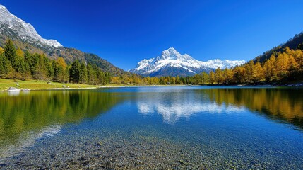 A picturesque lake reflects snow capped mountains under a clear sky