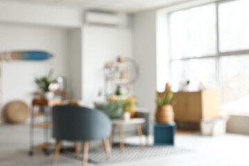 Blurred view of living room with sofa, shelf unit and green plants