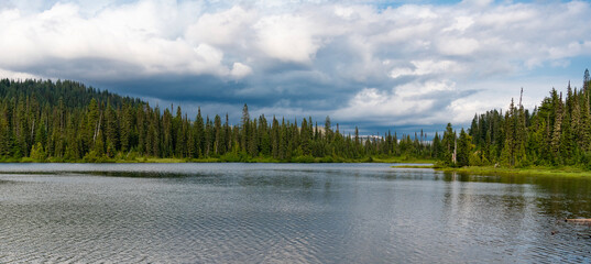 Scenic nature of hiking lake. Evergreen forest. Wilderness and adventure at forest. Lake with green landscape. Landscape of idyllic forest at lake. Nature panoramic landscape. Lake in scenic nature