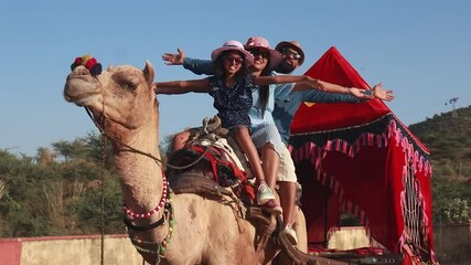 Young indian tourist family enjoying camel ride together having fun. People of india enjoy Rajasthan Safari Vacation and holidays.