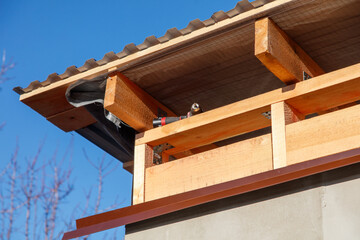 A roof with a wooden beam and a bird sitting on it