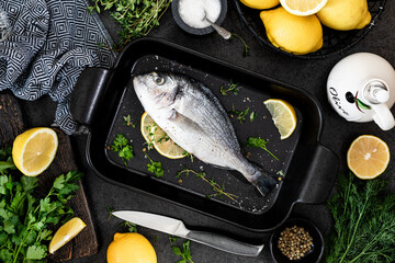 the concept of a delicious dinner. raw dorado fish with asparagus and lemon on dark background.
