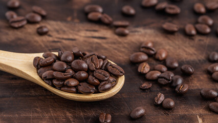 Wooden spoon filled with roasted coffee beans on a rustic wooden background. Concept of coffee culture, caffeine boost, and morning energy.