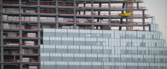 Workers are actively engaged in the construction of a new high-rise building in Paris, highlighting a mix of glass elements and steel structure. © FreeProd