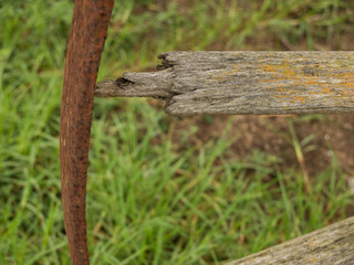 Old rusted wagon wheel with broken wooden spoke and green grass in background
