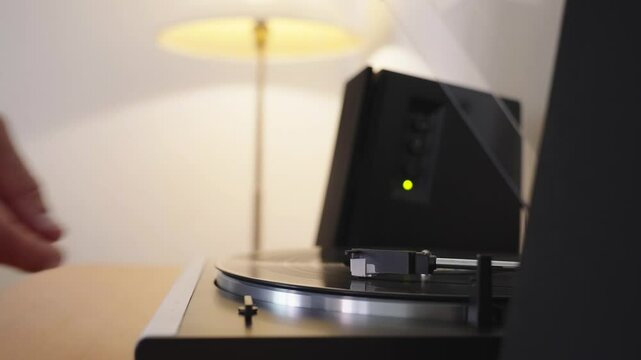 Starting the vinyl player by manual adjusting the tonearm with stylus. Hand turns on vinyl LP record. Analog classic HI-FI music listening