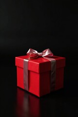 Obraz premium A single red gift box with a delicate pink ribbon, elegantly presented against a stark black backdrop, symbolizing a moment of anticipation and joyful surprise.
