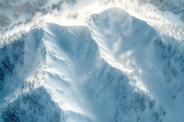 Aerial view of sunlit snowy mountain peaks surrounded by frosty forests, showcasing pristine wilderness and winter tranquility