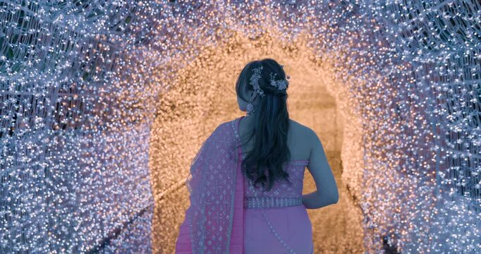 back view woman wearing traditional thai dress walking in light bulb tunnel 4k video.
