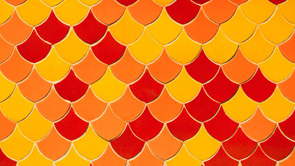 Colorful Fish Scale Pattern Background. Vibrant orange, red, and yellow ceramic tiles arranged in a traditional overlapping scale design. © RilakkuMaxx