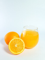 Fresh orange juice in a glass with whole and sliced oranges isolated on a white background