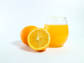 Fresh orange juice in a glass with whole and sliced oranges isolated on a white background