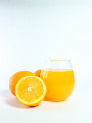 Fresh orange juice in a glass with whole and sliced oranges isolated on a white background