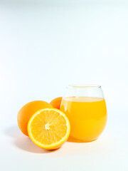 Fresh orange juice in a glass with whole and sliced oranges isolated on a white background