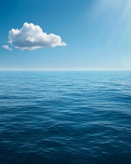 Obraz premium A vast, calm sea under the blue sky, with a white cloud in sky. The water is deep and serene, reflecting the clear sky above it. 