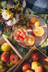 A picnic on a summer day with beautifully laid out fruits on wooden boards: ripe cherries, oranges, grapes and plums