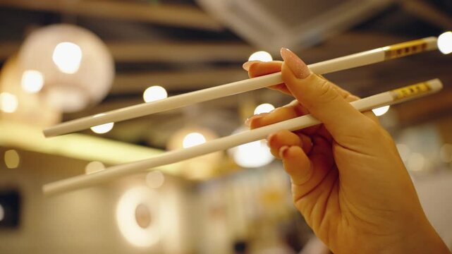 Woman hold chopsticks in Chinese restaurant ready to eat. Food sticks for asian cuisine, eating in traditional local cafe with street food in China. Translation: have a nice time