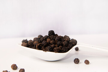 Black pepper seeds spoon isolated on white