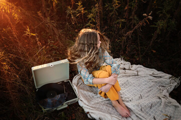 Above tween girl vintage record player in colorful field