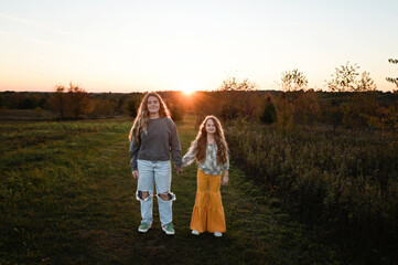 Beautiful sisters holding hands smiling under sunny sky