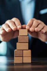 businessman’s hands carefully stacking wooden blocks into a structured pyramid, symbolizing corporate restructuring, mergers and acquisitions, business growth, and strategic planning