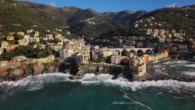 The colorful town of bogliasco in liguria, with crashing waves below, aerial view