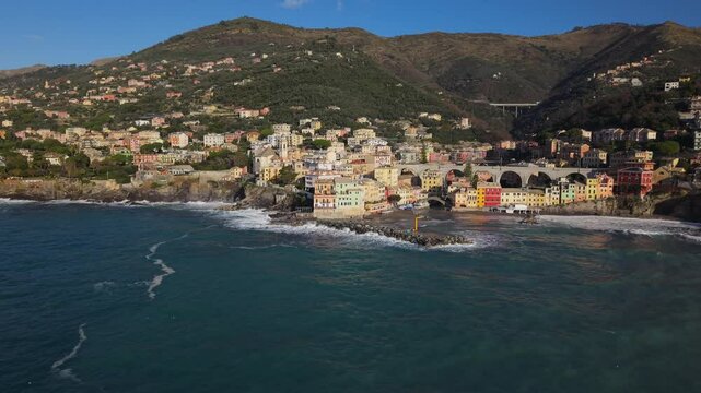 The colorful town of bogliasco with crashing waves and coastal hills, aerial view
