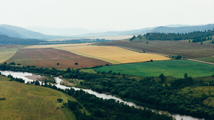 Obraz premium A tranquil river winding through rocky cliffs and dense forests, creating a breathtaking natural landscape captured in aerial drone footage