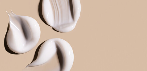 smears of creamy white texture cosmetic sample close up on beige background