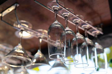 A row of wine glasses are hanging on a rack