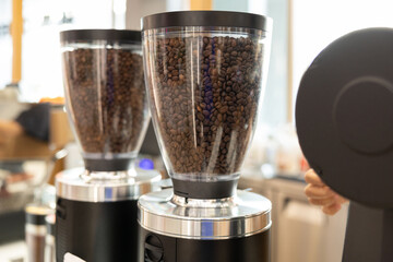 Two coffee grinders with a lot of coffee beans in them