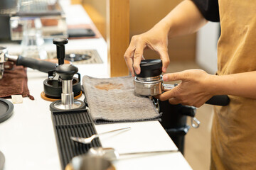 A barista is preparing a coffee drink with a coffee grinder