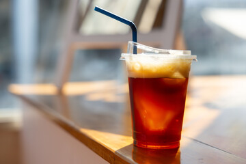 A cup of coffee with a straw in it sits on a wooden table