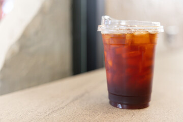 A cup of coffee with ice cubes in it sits on a table