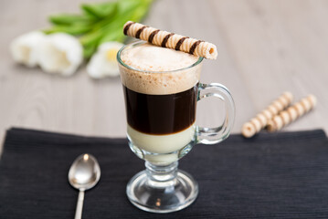 Coffee Bombon in a glass on the table with a waffle tube