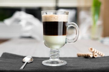 Coffee Bombon in a glass on the table with a waffle tube