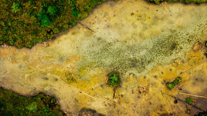 A serene thermal lake hidden in the dense forests of Siberia, surrounded by lush greenery and steaming waters, captured in aerial drone footage