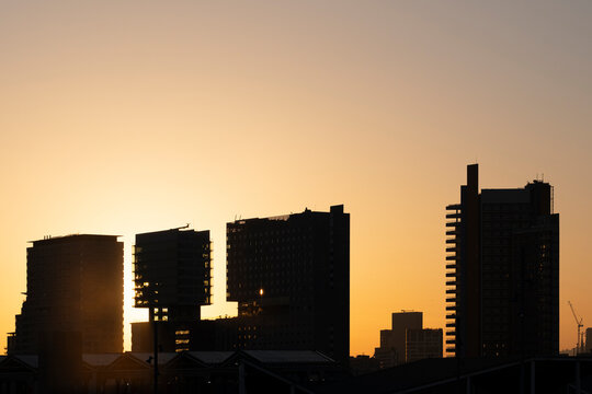 Urban skyline of Diagonal Mar, Barcelona, against a golden sky, showcasing modern skyscrapers and striking silhouettes.