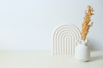 bouquet of dried wild flowers in white vase on background white wall