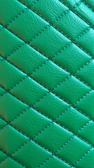 Fototapeta premium Green artificial leather surface texture, stitched in the form of rhombuses, squares, rectangles. Quilted eco-leather. 