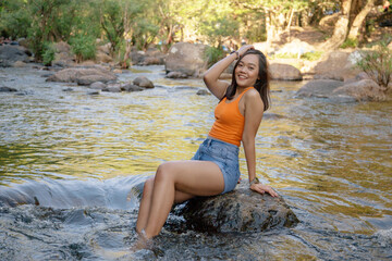 Asian woman happy in a refreshing mountain stream, surrounded by lush greenery