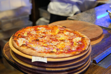 Homemade pizza with tomatoes, mozzarella and ham. Homemade Pizza on a rustic wooden table. Hot pizza slice with melting cheese on a rustic wooden plate.