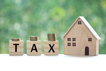 Tax concept,Model house with stack of coins money and tax word on green background,Business investment and Property tax concept