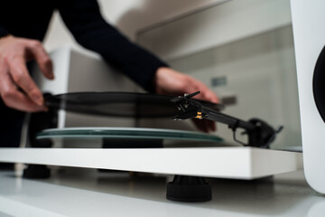 Music lover is under preparation vinyl player for playback. Musician hands are placing vinyl record on a turntable player.