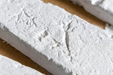 Close-up of textured white clay bricks arranged on a brown surface, their detailed patterns and rustic charm.