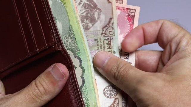 Closeup view of man's hands and wallet with Nepalese rupees banknotes.  Concept of saving money for retirement, cash settlement, financial success, literacy and income planning in Nepal.
