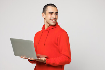 Young IT middle eastern man he wear red hoody casual clothes hold use work on laptop pc computer...